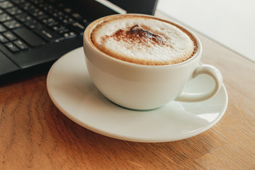 Freelancer working in cafe on a wooden counter bar with coffee mugs and laptop.