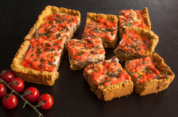 Rectangular quiche with salmon, spinach and cream on a black wooden table. French cuisine.