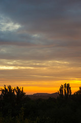 Landscape with dramatic light - beautiful golden sunset with saturated sky and clouds.