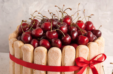 Cherry cake of French Savoyard cookies with whipped cream, decorated with fresh cherry berries. Summer cake. Free space for text