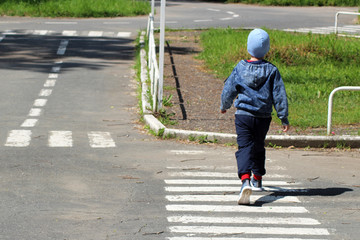 The boy is at a pedestrian crossing, the rules of the road, the view from the back