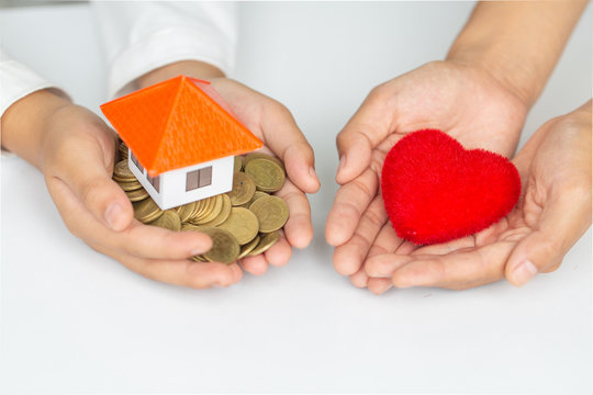 closeup picture of female hands holding model house and red heart. charity, real estate and family home concept.
