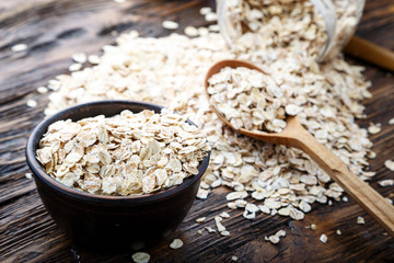 Spoon and bowl with raw oatmeal on the table. Top view, horizontal.