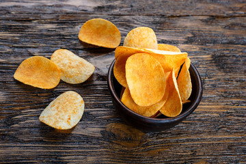 Crispy potato chips in bowl on old kitchen table