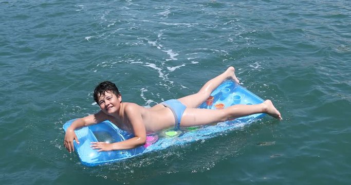 Portrait of a  cute happy boy in swimming suit with inflatable matress enjoying summer day