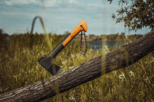 Tourist or camping hatchet stuck in a wooden log after chopping, tourist or hiking or survival or lumberjack tool