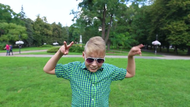 Silly dance of funny kid. Closeup portrait of cute funny little white boy posing before camera wearing sunglasses. 10 years old boy looking at camera cheerfully. Real time full hd video footage.