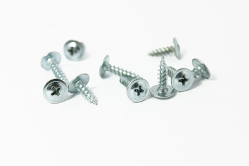 Self-tapping screws as white construction tools for wood close up on a white background.