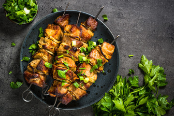 Grilled meat with herbs on black top view.