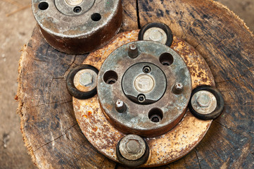 Vintage rusty mechanics with scratched copper gears and old round elements inside. Grungy copper and rusty metal textures on aged scratched wooden stump surface background. Rough brown backdrop