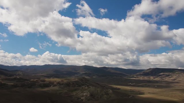timelapse with flying white clouds above the hills