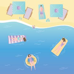Girls on inflatable mattresses swim in sea,umbrellas and deck chairs on the beach