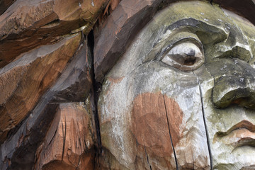 a fragment of an old wooden statue damaged by the time and nature - a close-up face. Folk art, paganism, ceremonies, sign.