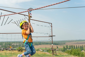 A boy dressed in a protective helmet and insurance, goes down the rope, descends holding a protective cable.