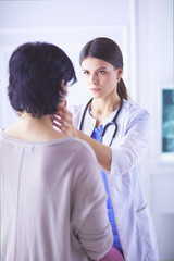 A serious female doctor examining a patient's lymph nodes