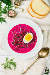 Cold beetroot soup. Holodnik.Traditional Lithuanian (ukrainian, russian, polish) red beet soup. Cold borscht served with cucumbers, dill and eggs on a white rustic background with bread