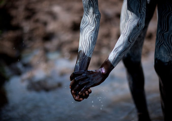 Clay body paintings on suri warriors before donga stick fighting, Turgit village, Omo valley, Ethiopia