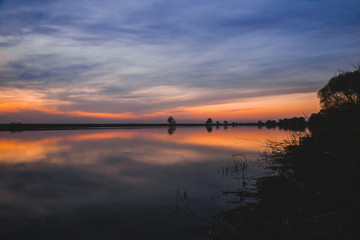 Large panorama of the most beautiful, scarlet sunset over the river in the spring