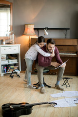 Cute little girl and her handsome father are playing guitar and smiling while sitting  in the room