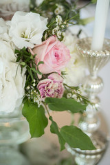 The wedding table setting for the newlyweds is decorated with fresh flowers of carnation, rose, anthurium and eucalyptus leaves. Silver candlesticks, white candles. Wedding floristry. Close-up details
