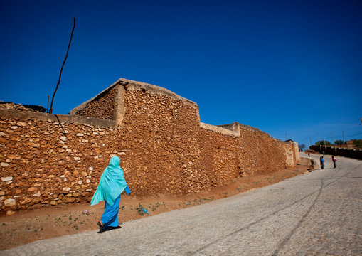 Blue-dressed woman passing by the old walls, Harar, Ethiopia