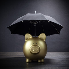 Gold Piggy bank with umbrella concept for finance insurance, protection, safe investment or banking