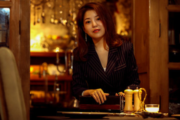 Asian mature sexy female sitting in cafe reading a book