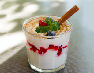 Delicious dessert with fresh berries, mint and cinnamon in a glass beaker