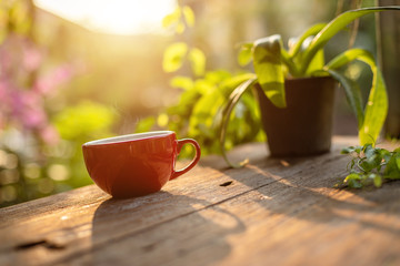 Red coffee cup on wooden table morning nature light in garden concept