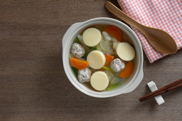 top view of egg tofu clear soup in a ceramic bowl on wooden table. asian homemade style food concept.