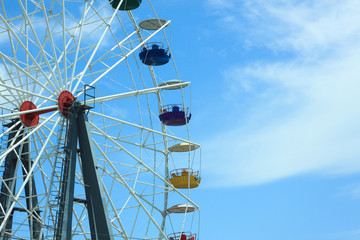 Multicolour ferris wheel on blue sky background. Copy space, street photography.