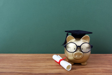Gfold piggy bank with a grad cap and diploma in front of green chalkboard. Education scholarship - obrazy, fototapety, plakaty