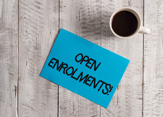 Text sign showing Open Enrolments. Business photo showcasing when employees may make changes to elected fringe benefit Pastel Colour paper placed next to a cup of coffee above the wooden table