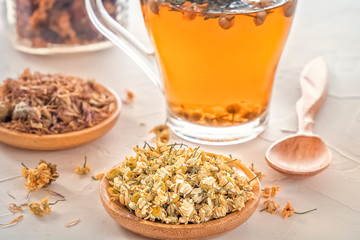 Herbal tea with pharmaceutical chamomile, dry chrysanthemum and hunters on a white table
