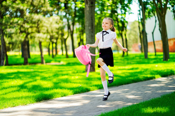 Portrait of happy Caucasian young smiling girl wearing school backpack outside the primary school. schoolgirl, elementary school student runs jumping from school, graduation, summer holidays.