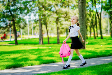 Portrait of happy Caucasian young smiling girl wearing school backpack outside the primary school. schoolgirl, elementary school student runs jumping from school, graduation, summer holidays.