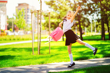 Portrait of happy Caucasian young smiling girl wearing school backpack outside the primary school. schoolgirl, elementary school student runs jumping from school, graduation, summer holidays.