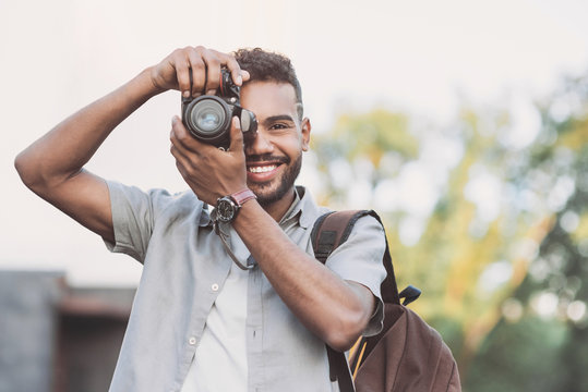 Young man photographer takes photographs with dslr camera in a city. Travel, vacations, professional freelance work and active lifestyle concept
