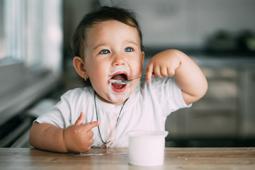 A little charming girl eats yogurt all smeared herself