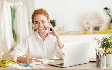 Fashion Designer Talking On Phone And Working On Laptop