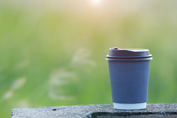 Coffee paper cup with green nature background.