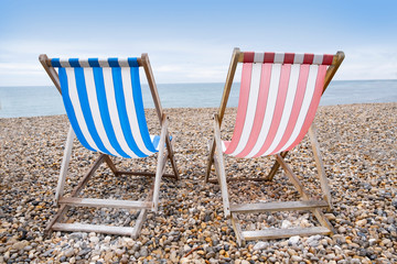 Deckchairs on beach, typical english seaside holiday scene, red and blue stripes representing main political party of labour or conservative