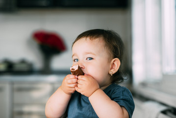 little girl in the afternoon in the kitchen eating a delicious chocolate bar