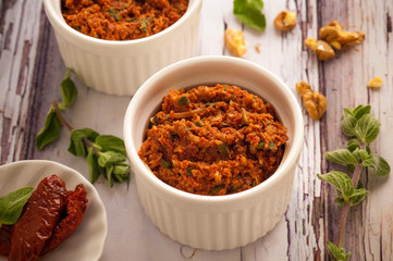 Red pesto sauce. Classic Italian sauce with dried tomatoes, nuts and fresh herbs. Serve in a small white bowl. Close up and horizontal orientation. - obrazy, fototapety, plakaty