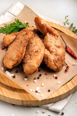 Chicken nuggets in breading. Served on a wooden plate with fresh vegetables and herbs. Close up and vertical view.