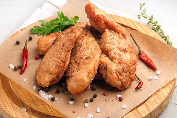 Chicken nuggets in breading. Served on a wooden plate with fresh vegetables and herbs. .Close up and horizontal view.