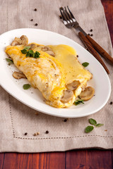 French omelet with mushrooms and cheese. A large portion is served on a white plate. Close up and vertical orientation.