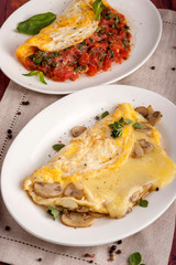 French omelet with mushrooms and cheese. Omelet with tomatoes. A large portion is served on a white plate. Close up and vertical orientation.