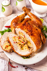 Stuffed homemade boneless chicken. A large cut portion on a white dish and wooden table. Close up and vertical view.
