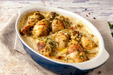 Fried chicken cooked in a creamy sauce with garlic. Large portion in a deep dish. Close up and horizontal view.